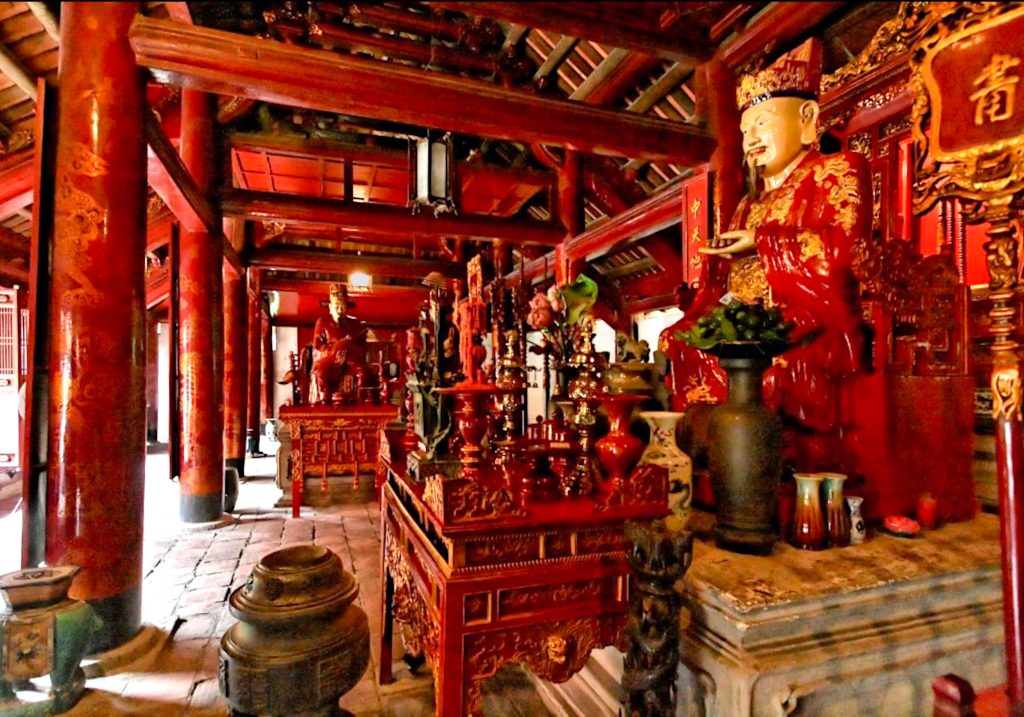 Interior of an ornately decorated temple, with a large statue of a seated Confucius.