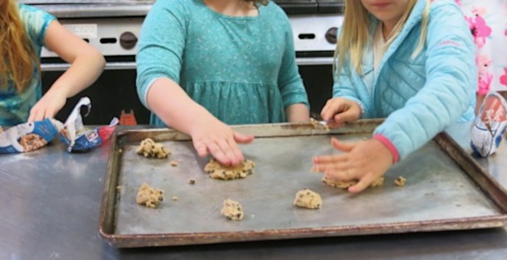 Children placing dough onto a baking sheet.