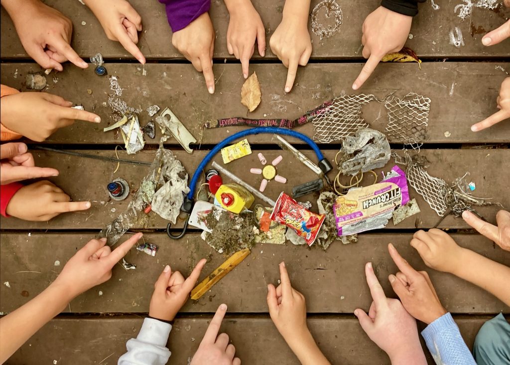 Hands of a dozen children pointing to trash they picked up