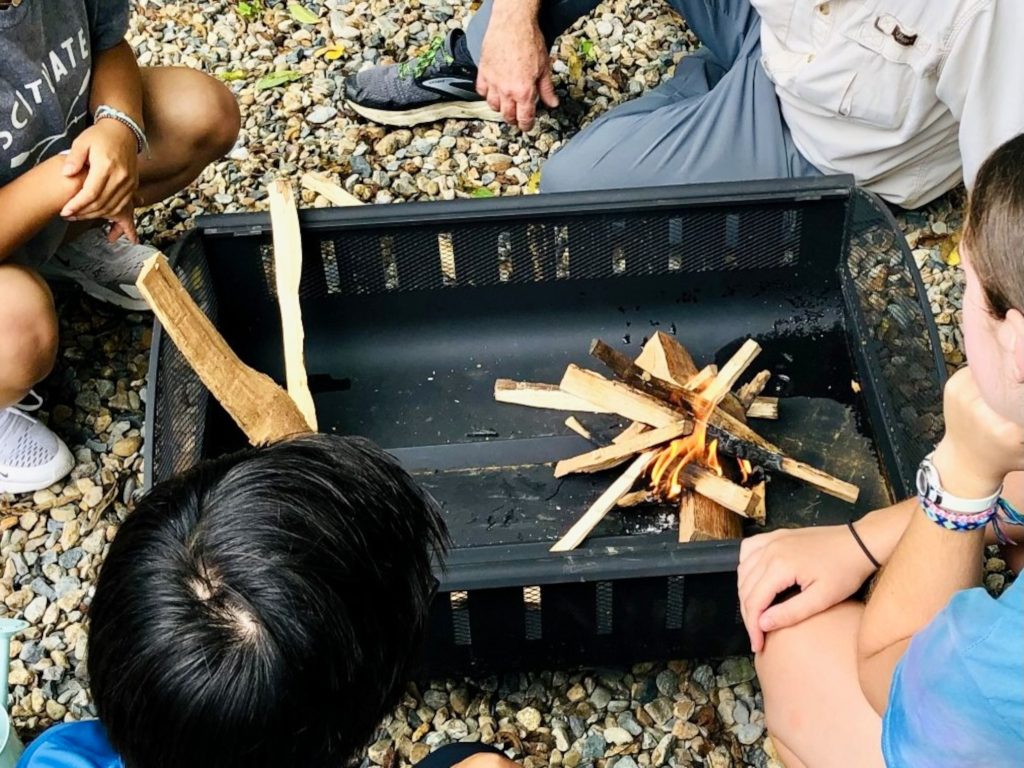 People around a fire pit, with a small fire burning.